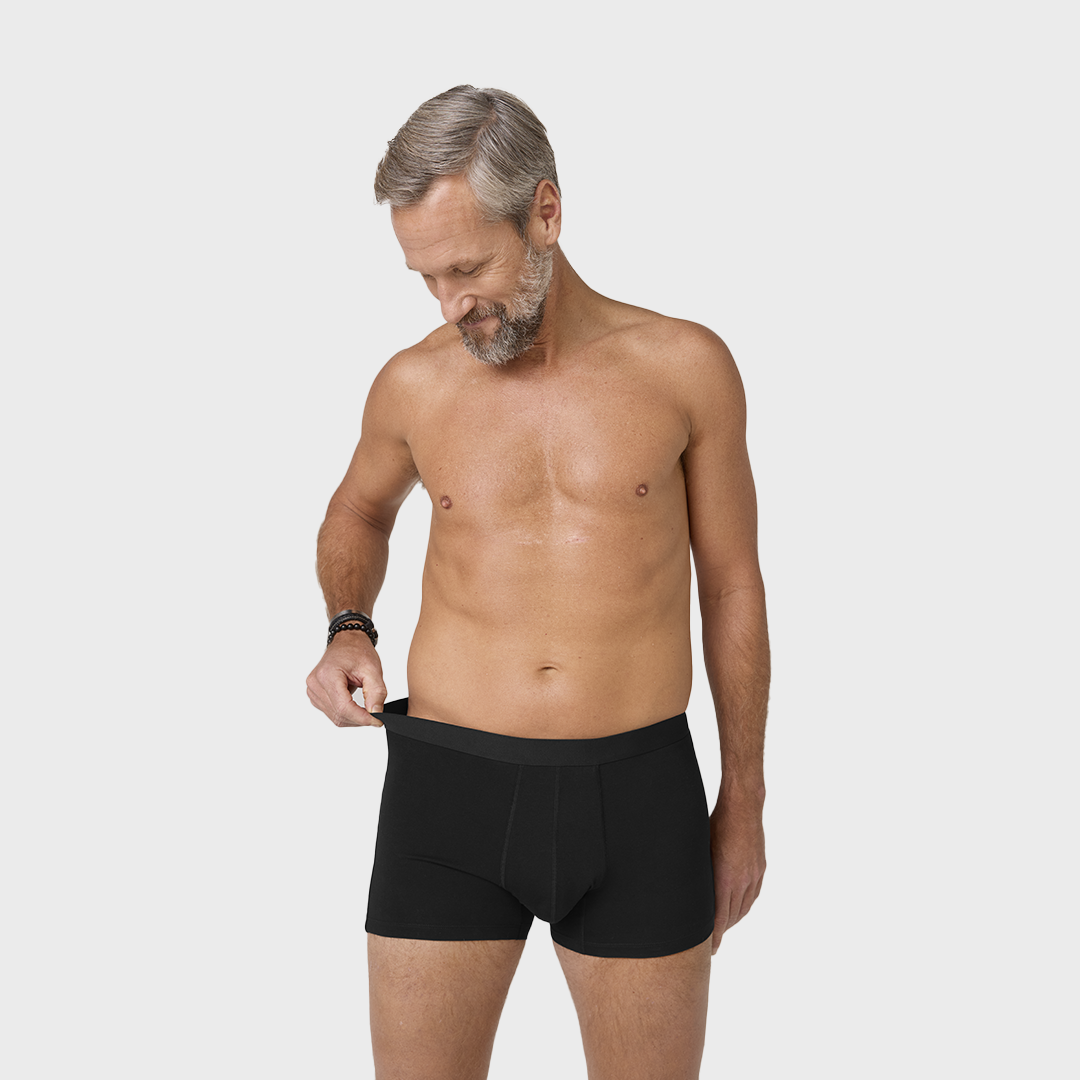 Man wearing NEW TENA Men Protective Boxers Light, showcasing the fit and design of washable incontinence boxers made from organic cotton with an elastic waistband.